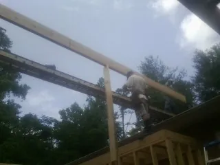 Carpenter setting a ridge beam over a new addition frame — Ice Dam Removal by Roofing Brothers in Mc Grann