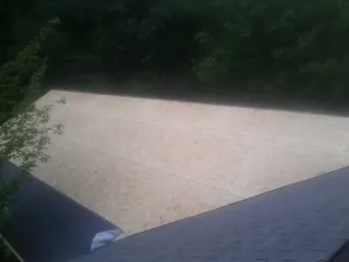 New OSB roof sheathing installed beside an existing shingle roof in Mc Grann