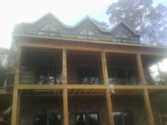 Dormers and porch framing on a large log home under construction — Roof Coating work by our crew in Mc Grann