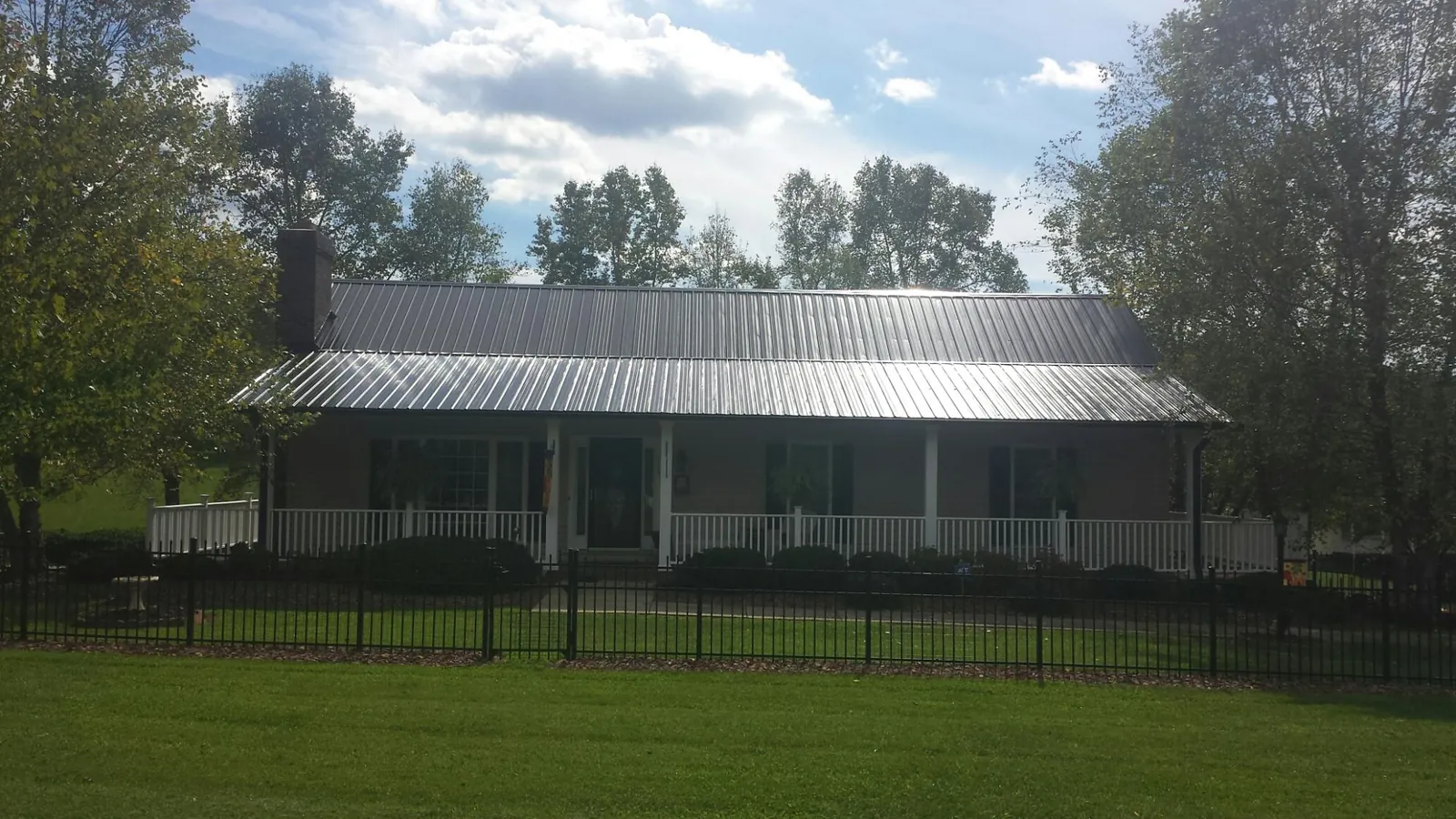 Gray metal roof on a brick ranch with a full width front porch — Gutter Guard Installation work by our crew in Mc Grann