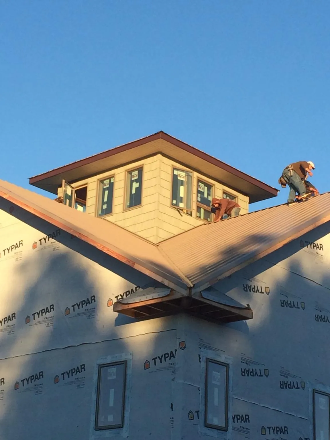 Roofers working around a rooftop cupola on a new metal roof at sunset — Roof Waterproofing in Mc Grann by Roofing Brothers
